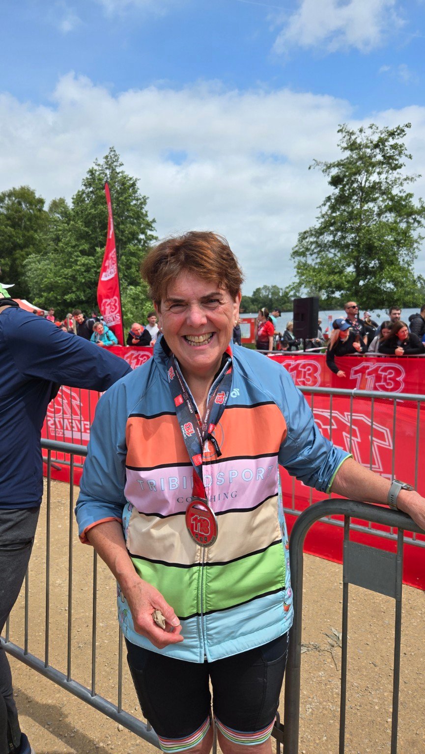 Louise, a Tribirdsport athlete, smiling in Tribirdsport kit with her medal